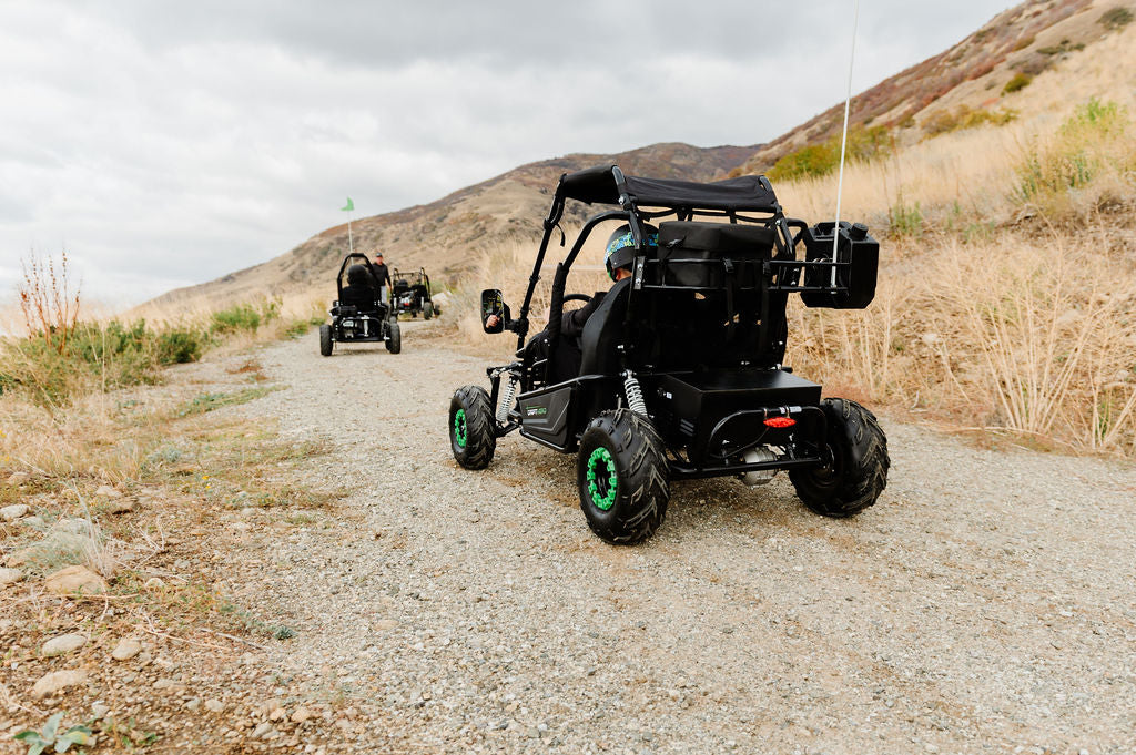 Riders wearing helmets driving Drift Hero electric go-karts on an off-road gravel trail
