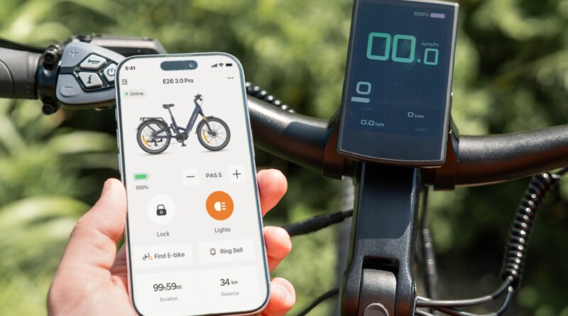 Hand holding a phone with the ENGWE app next to the E26 3.0 Pro handlebar display