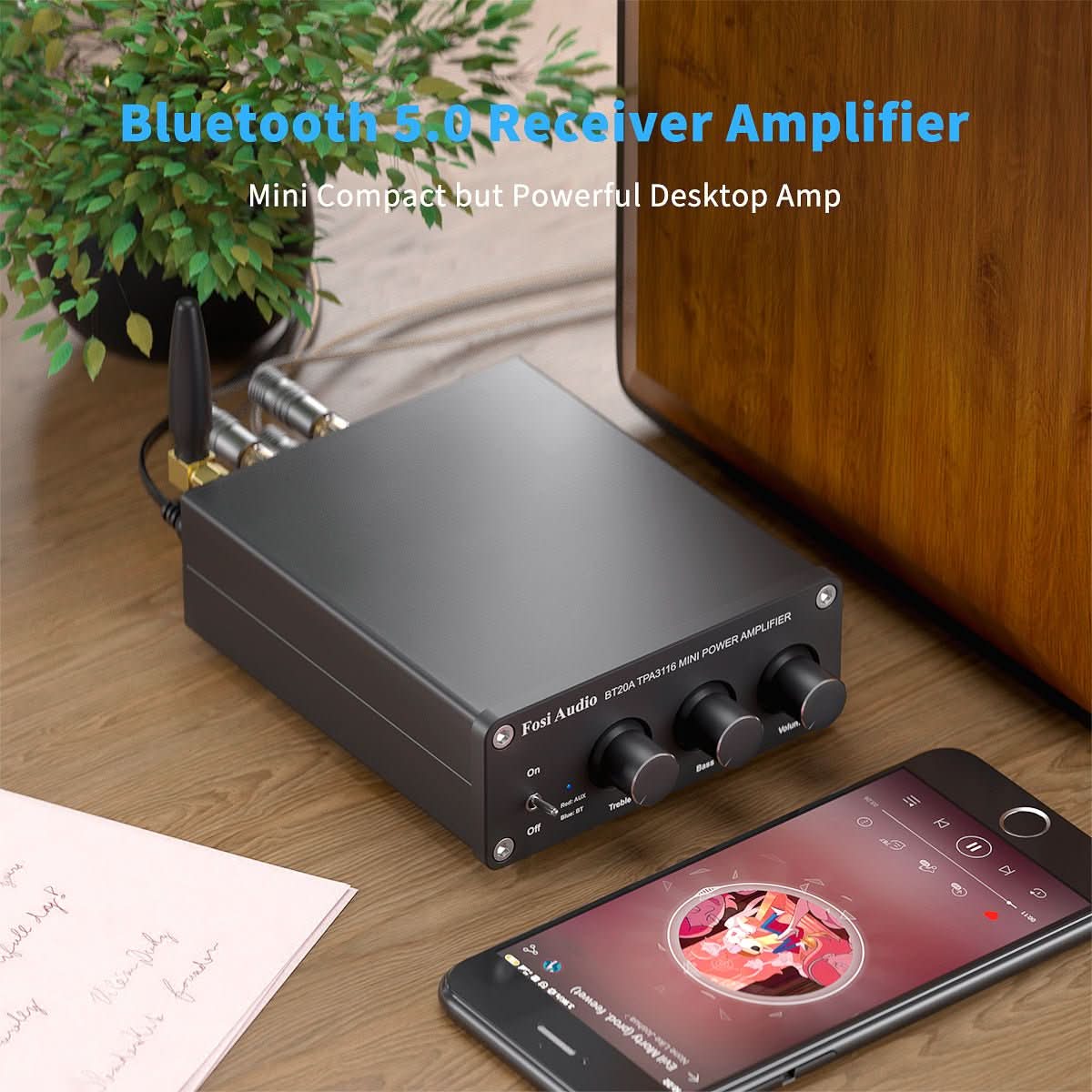 Fosi Audio BT20A amplifier set up on a desk next to a wooden speaker and a phone streaming music